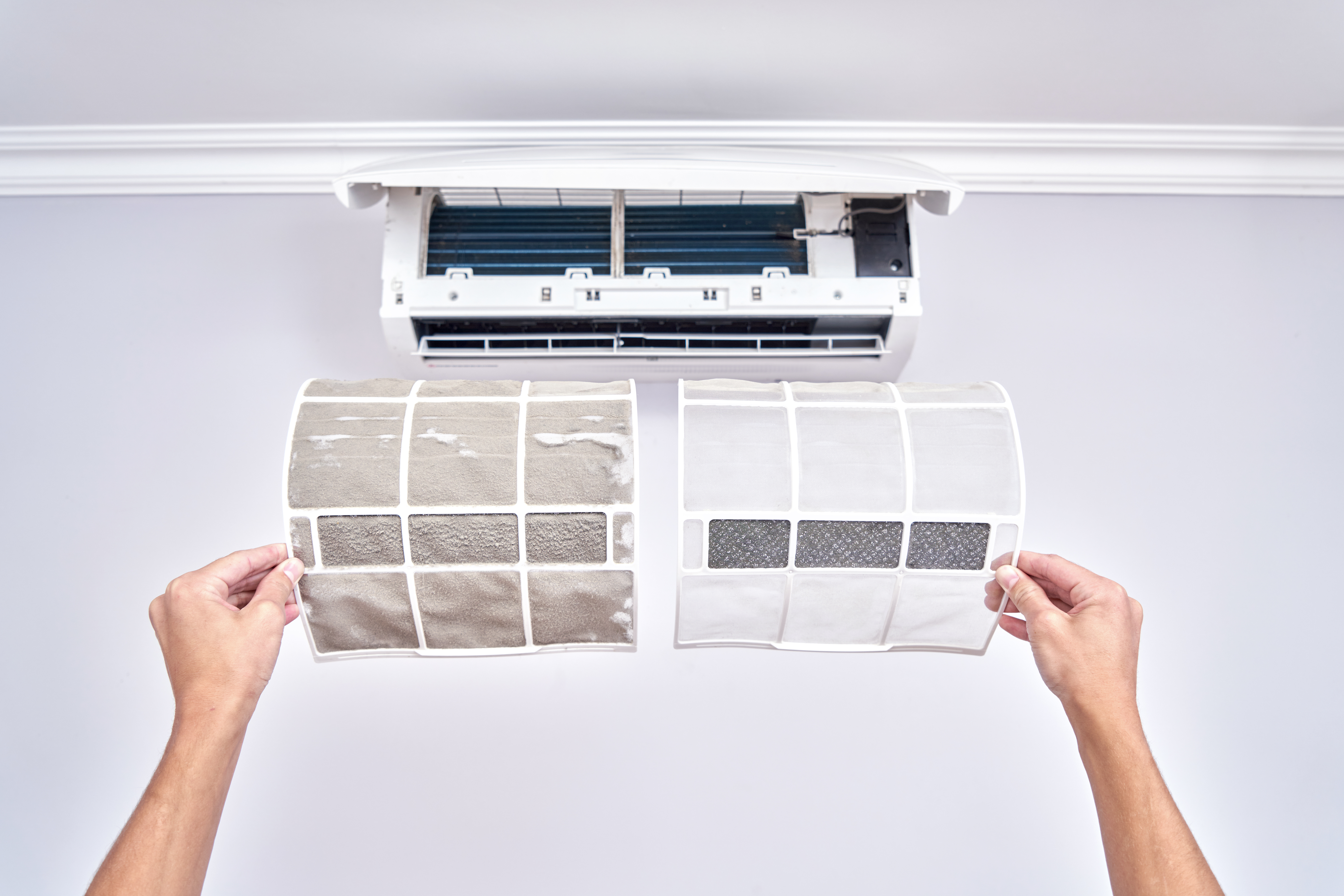 a close up of a dirty and clean air filter in an ac unit shows that regular ac maintenance is needed to avoid sickness