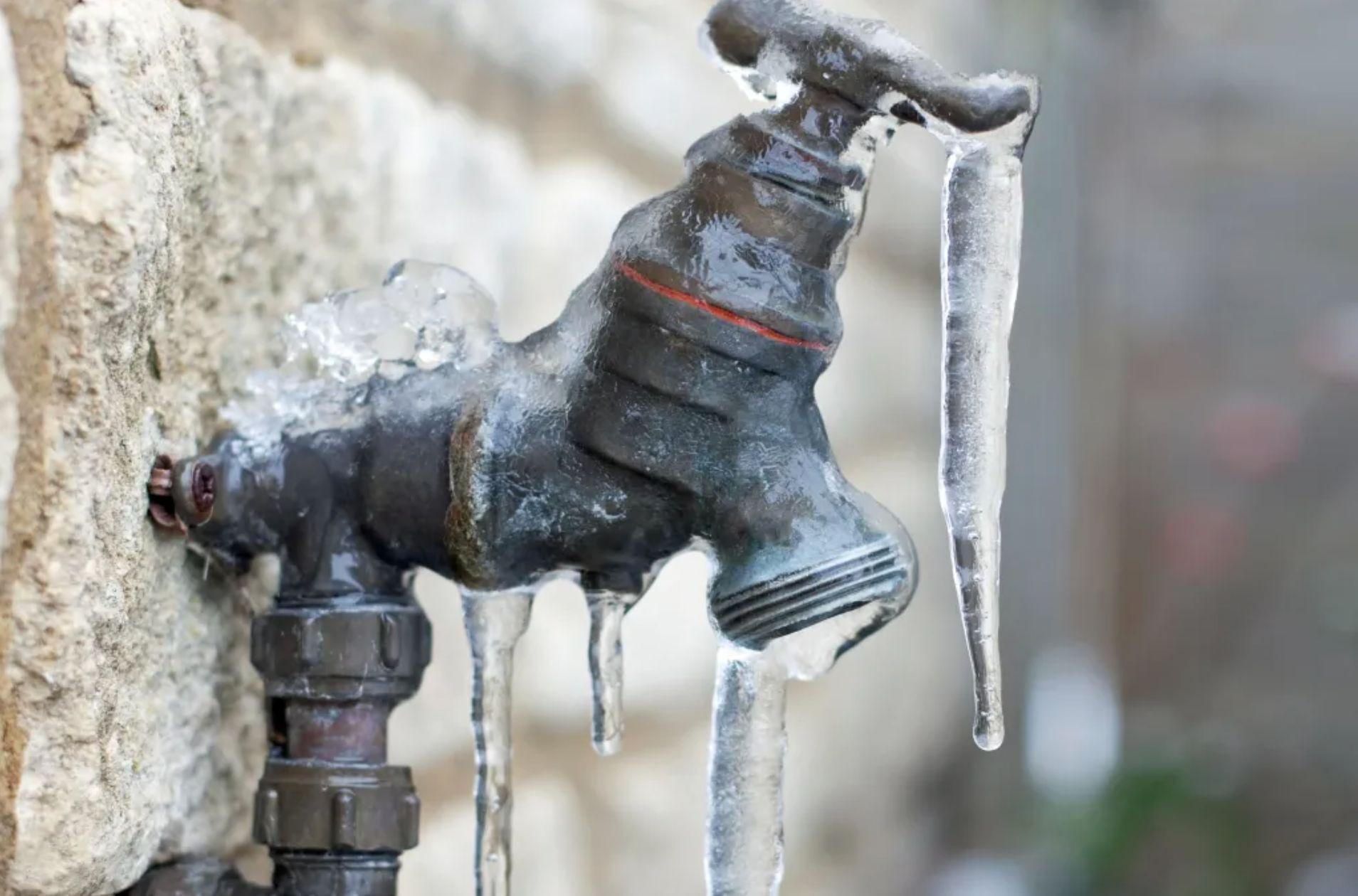 a frozen tap uncovered and attached to a house during a vernon bc winter