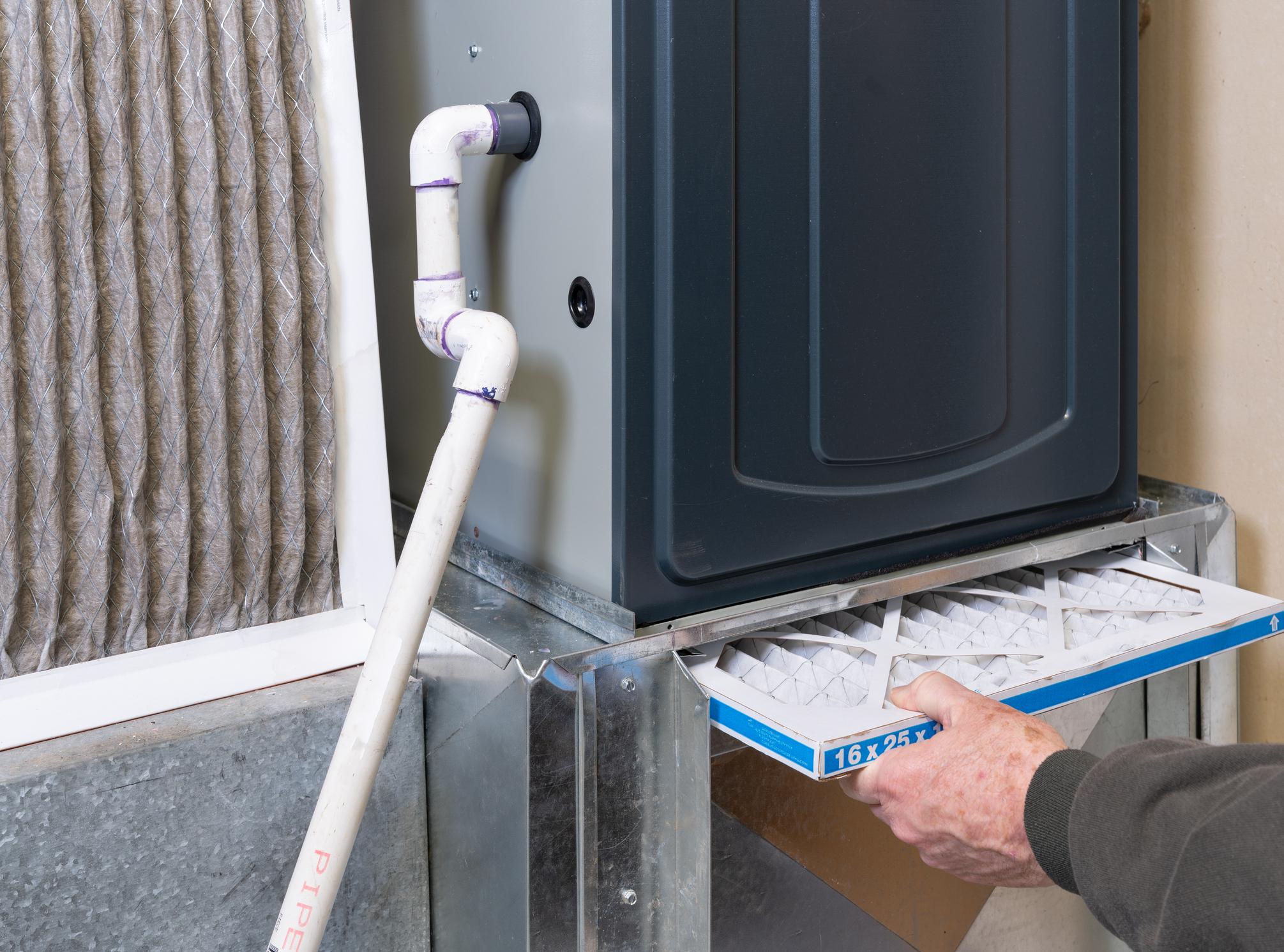 Replacing dirty furnace filter in home by man